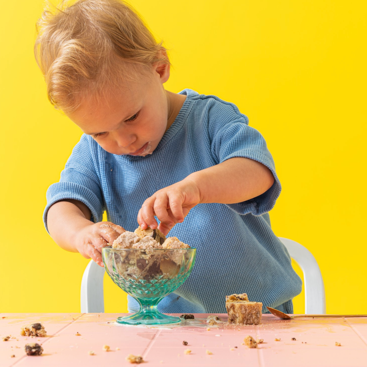 Small boy eating wandel with hands from pedestal bowl