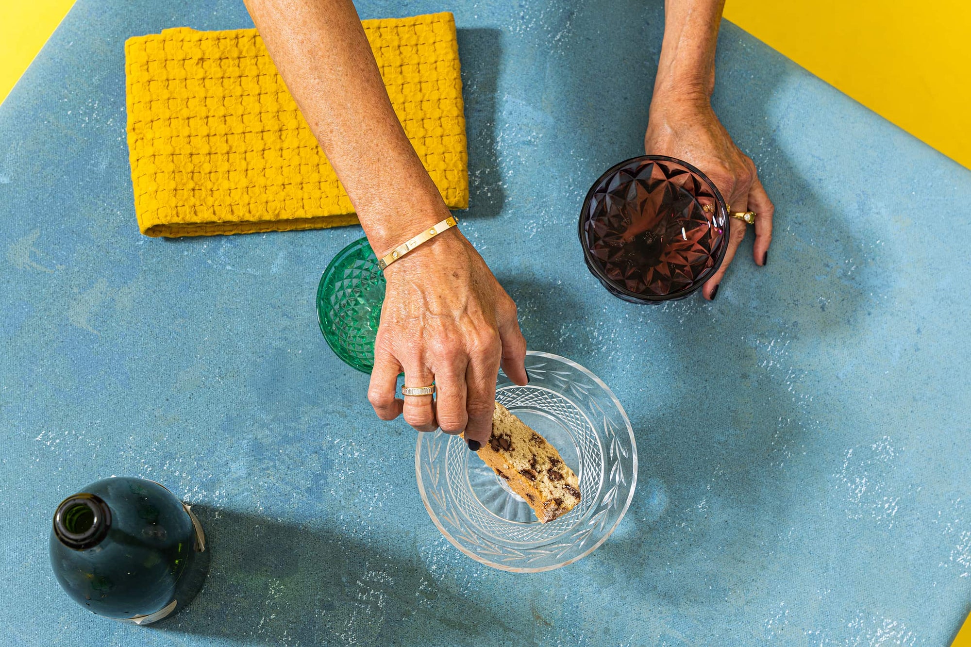 A women's hand reaching for a slice of Wandel in one hand and holding a cocktail in the other